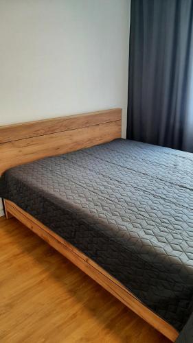 a bed with a wooden frame in a room at Apartament Broniewskiego 50m Centrum Nowy Sącz in Nowy Sącz