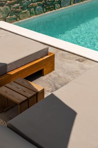 a pool with a bench next to a swimming pool at Cycladic Breeze Villas in Kampos Paros