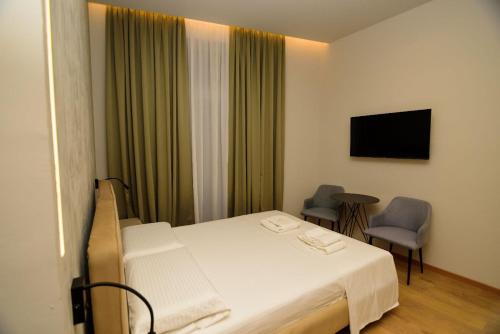a bedroom with a bed and a window with a television at Hotel Zeneli Vlore in Vlorë