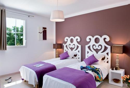 duas camas num quarto com roxo e branco em Lagrange Vacances - Le Clos Savornin em Saint-Saturnin-dʼApt