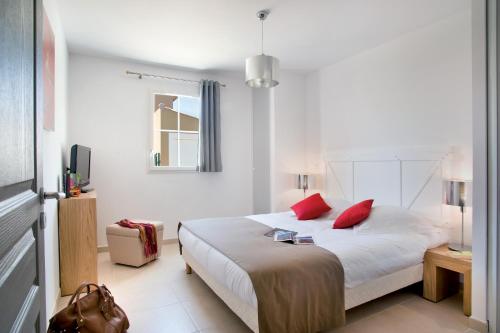 a white bedroom with a bed with red pillows at Lagrange Vacances - Le Clos Savornin in Saint-Saturnin-les-Apt