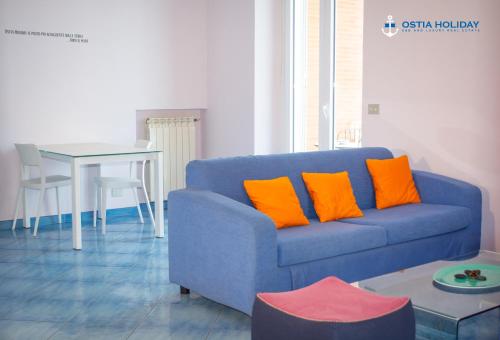 a blue couch with orange pillows in a living room at Ostia Holiday Al Curvone 2 in Lido di Ostia