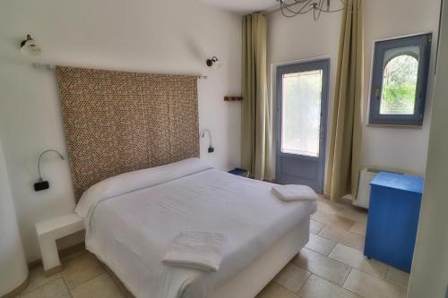 a bedroom with a white bed and a window at Masseria Trullo Sovrano Exclusive B&B in Cisternino