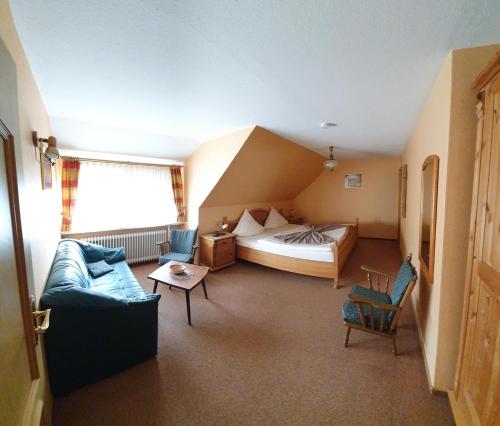 ein Hotelzimmer mit einem Bett, einem Sofa und einem Stuhl in der Unterkunft Pension Bergfrieden in Schmallenberg