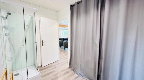 a bathroom with a walk in shower and a glass door at Chalet avec terrasse sur pilotis vue sur l'étang in Rue