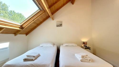 two twin beds in a room with a window at Chalet avec terrasse sur pilotis vue sur l'étang in Rue