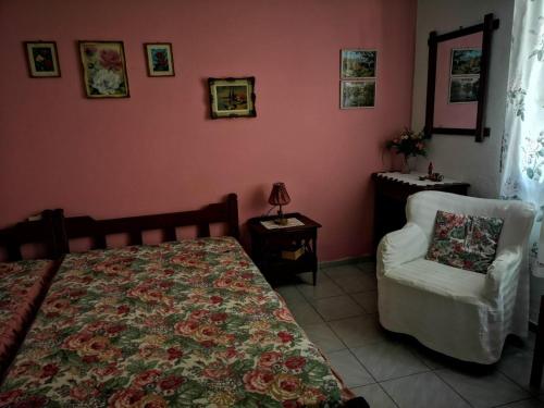 1 dormitorio con 1 cama y 1 silla blanca en Maria's Studios pink, en Áfissos