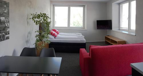 Habitación con cama y sofá rojo en Replay apartmány, en Frenštát pod Radhoštěm