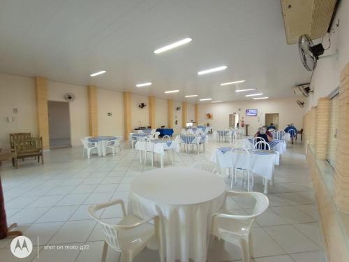 Habitación con mesas blancas y sillas blancas. en Hotel Beira Rio en Aquidauana