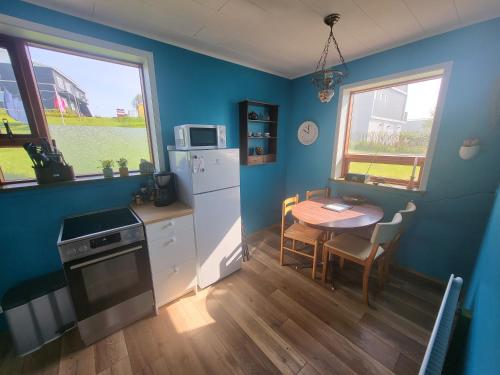 uma cozinha com uma mesa e um frigorífico branco em Ásgarður em Hrísey