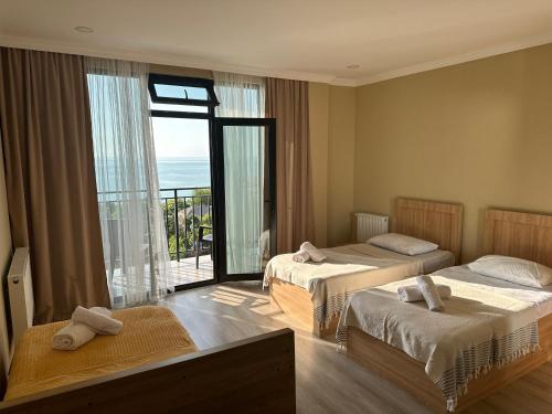 een hotelkamer met 2 bedden en een balkon bij Guest House ETM in Makhinjauri