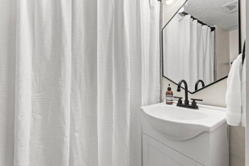 a white bathroom with a sink and a mirror at The Luxe/Hot Tub/12min to Horse Park/30 Min to Ark in Georgetown