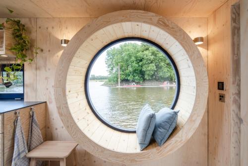 a circular window in a hobbit house with water at Hausboot AHOI hochwertiges Hausboote mit großer Terrasse und Kamin in Hamburg