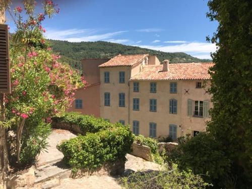 a large building on top of a hill with flowers at L Estello, Village house in Provence in Seillans
