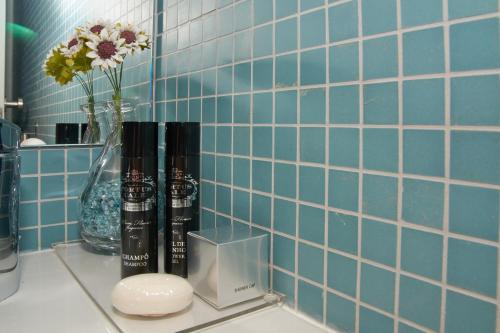 a bathroom counter with blue tiles and a vase with flowers at Bolhão Nobre Apartments in Porto