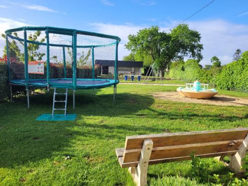 a park with a playground with a slide and a bench at Le Clos Tranquille in Saint-Cast-le-Guildo