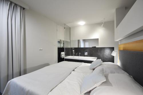 a white bedroom with a large bed and a sink at Apartament Mare Baltico in Pogorzelica