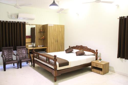 a bedroom with a bed and two chairs at Indian Residency in Tiruchirappalli
