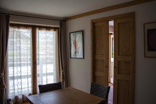 a dining room with a table and two windows at Maison Carrel Elegant 7 in Breuil-Cervinia
