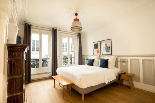 a bedroom with a large white bed with blue pillows at Edgar Suites Martyrs - Lebas in Paris