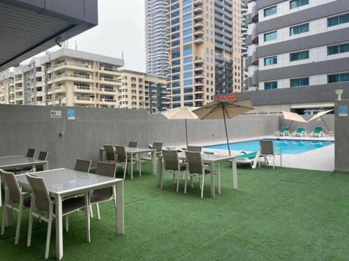 um pátio com mesas e cadeiras e uma piscina em Spacious Cozy Brand New 1 Bedroom Apartment em Dubai