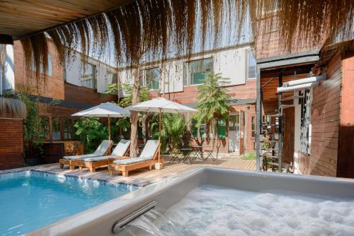 a swimming pool with chairs and umbrellas next to a building at Verde Madera Hostel B&B in Santiago