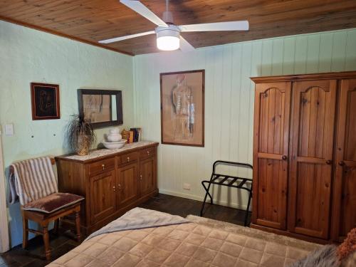 a bedroom with wooden furniture and a ceiling fan at Little Para Cottage Tanunda in Tanunda