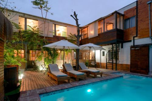 a pool with chairs and umbrellas next to a building at Verde Madera Hostel B&B in Santiago