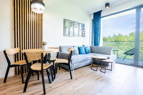 - un salon avec un canapé, une table et des chaises dans l'établissement Apartamenty Olimpijska z widokiem na jezioro, à Olsztyn