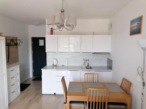 a kitchen with white cabinets and a table and chairs at Do Morza 1 in Mechelinki