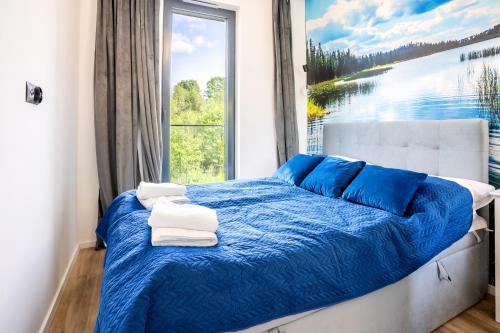 sypialnia z łóżkiem z niebieską pościelą i oknem w obiekcie Apartamenty Olimpijska z widokiem na jezioro w Olsztynie