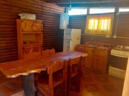 a kitchen with a wooden table and a refrigerator at Cabañas Achalay in Valle Hermoso