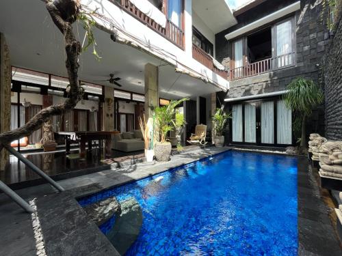 uma piscina no meio de uma casa com água azul em Rahayu Guest House Seminyak em Seminyak