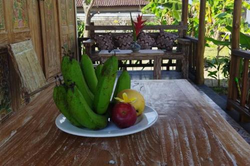 a plate of bananas and apples on a wooden table at Pondok widji in Sukawati