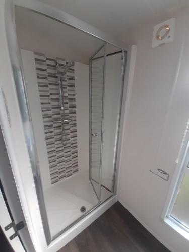 La salle de bains est pourvue d'une douche à l'italienne et d'une porte en verre. dans l'établissement Mobilhome Vias Plage la Carabasse, à Vias