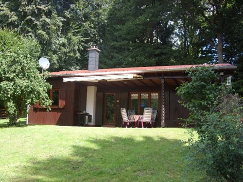 a cabin with chairs and a table in a yard at Ferienhaus Am Wäldchen in Weiskirchen