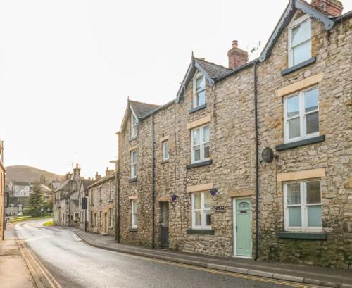 an old stone building on a city street at Happy Feet Cottage, Sleeps 6 in Bradwell