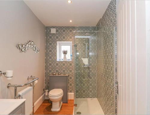 a bathroom with a toilet and a glass shower at Happy Feet Cottage, Sleeps 6 in Bradwell