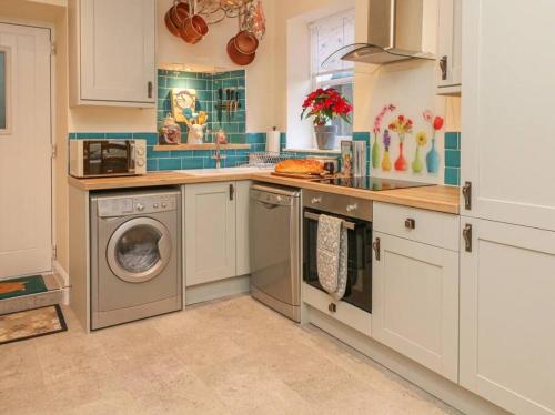 a kitchen with a washing machine and a dishwasher at Happy Feet Cottage, Sleeps 6 in Bradwell