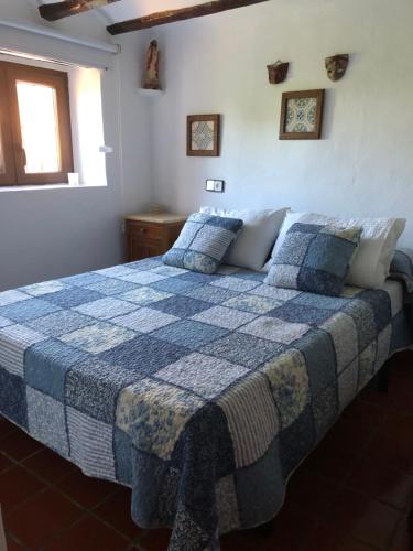 um quarto com uma cama com um cobertor azul e branco em El Refugi em Vilafamés