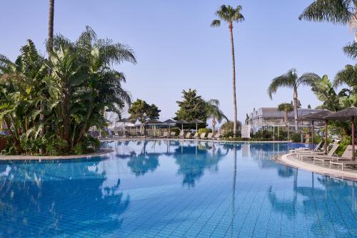 een groot zwembad in een resort met palmbomen bij Atlantica Bay - Adults Only in Limassol