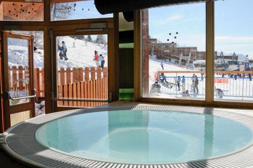 a hot tub in a room with a view of a ski slope at Lagrange Vacances Le Roc Belle Face in Arc 1600