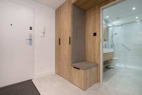 a bathroom with a wooden door with a bench in it at Apartament Premium PINEA 205 in Pobierowo