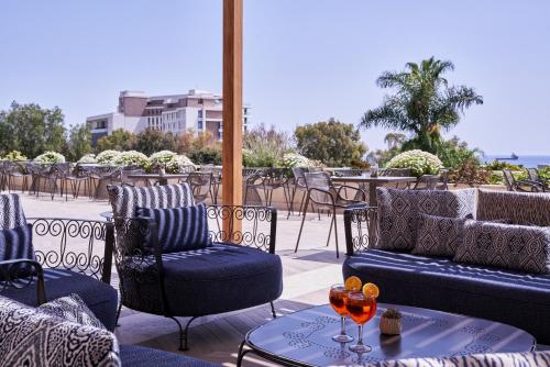 a patio with chairs and a table with wine glasses on it at Atlantica Bay - Adults Only in Limassol