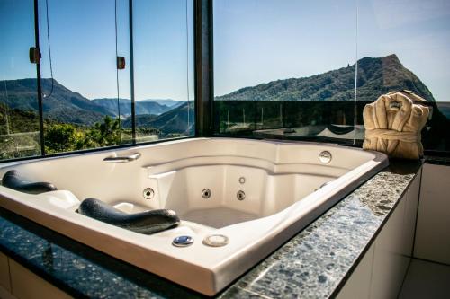 a bath tub sitting on top of a counter with windows at Caminho das Nuvens - Cabanas de Montanha in Bom Retiro