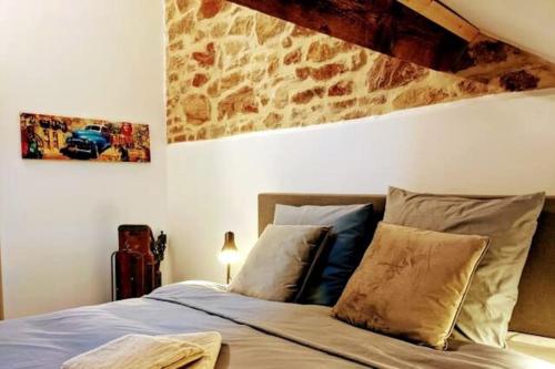 a bedroom with a bed with a stone wall at L’atelier central - Polleur - Duplex Terrasse 8 p in Theux