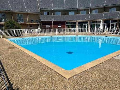 une grande piscine bleue devant un immeuble dans l'établissement Appartement Le Freya avec terrasse à 5 min Honfleur - Piscine - Parking - Wifi, à Équemauville