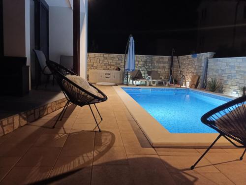 a swimming pool with two chairs next to at Kuća za odmor MARIA in Vodice