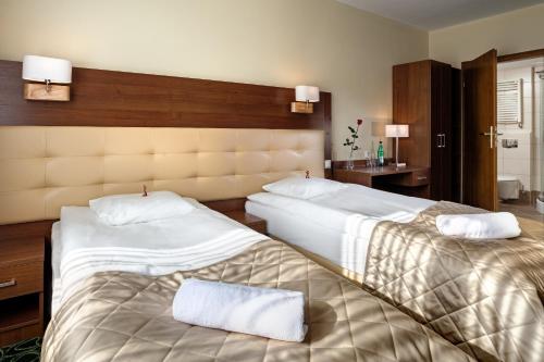 Cette chambre d'hôtel comprend 2 lits avec des draps blancs. dans l'établissement Hotel Royal Botanic, à Lublin
