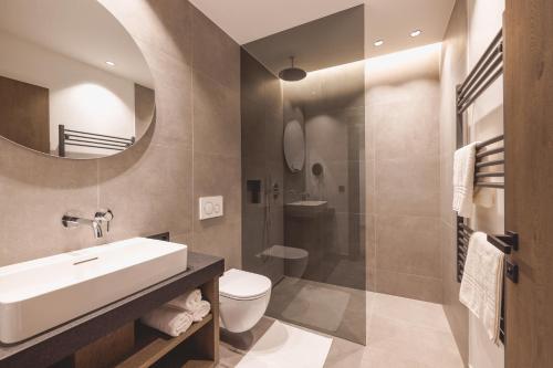 een badkamer met een wastafel, een toilet en een spiegel bij Thalhof Apartments in Brixen im Thale